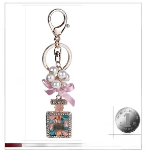 Dettaglio del fiocco rosa e cinturino di perle con ciondolo a boccetta di profumo con strass