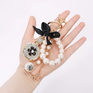 Luxury keychain with pearls, black bow, camellia charm, and Eiffel Tower pendant