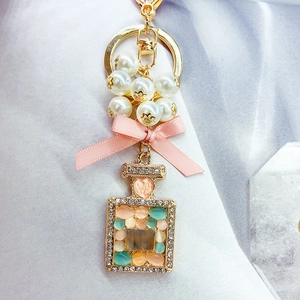 Portachiavi boccetta di profumo elegante con pietre opali, fiocco rosa e perle