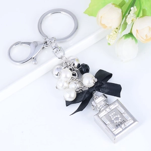 Elegante portachiavi con fiocco di perle e ciondolo a boccetta di profumo con strass