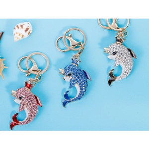 Detail of dolphin bag charms with crowns and colorful rhinestones on blue beach background