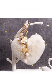 Détail d'un porte-clés cœur blanc en peluche avec pendentif doré et décor de perles