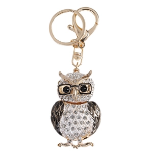 Porte-clés chouette dorée avec strass blancs et lunettes noires sur fond blanc