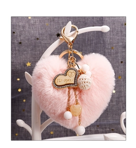 Détail d'un porte-clés cœur rose en peluche avec fermoir doré et breloques perlées