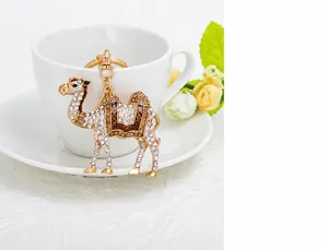 Detailansicht eines goldenen Kamel-Schlüsselanhängers mit Kristallen an einer weißen Tasse