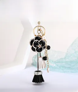 Détail du porte-clés fleur de camélia noir avec chaîne de perles et pompons élégants