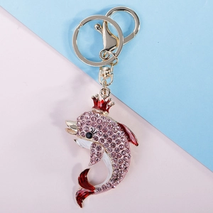 Pink rhinestone encrusted dolphin keychain with red crown on pastel background