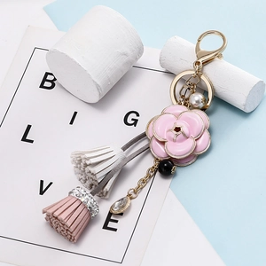 Détail du porte-clés camélia rose avec glands en cuir et breloque perle élégante