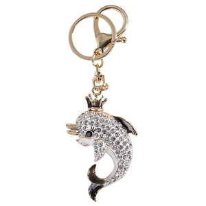 Sparkling dolphin keychain with crown, golden metal base and clear rhinestones on white background