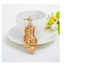 Détail du porte-clés hibou doré avec découpe en cœur sur une tasse blanche élégante