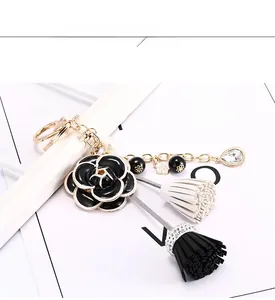 Détail du porte-clés fleur de camélia noir avec pompons et chaîne dorée de perles