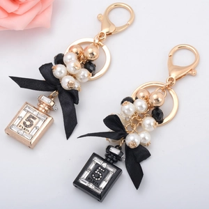 Elegante portachiavi a boccetta di profumo con perle fiocco nero e strass scintillanti