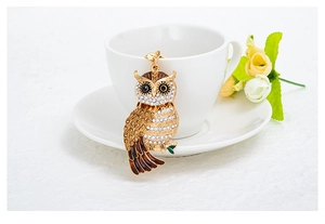 Gros plan d'un porte-clés hibou doré orné de strass suspendu à une tasse en céramique blanche