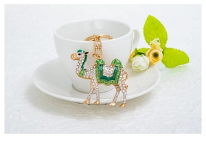 Detailansicht Kamel Schlüsselanhänger mit grünem Emaille und Strass auf einer Tasse