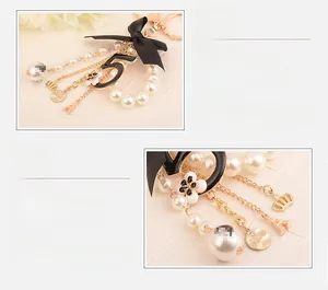 Detail of luxury fashion keychain with pearl chain, black bow, and gold Eiffel Tower charm