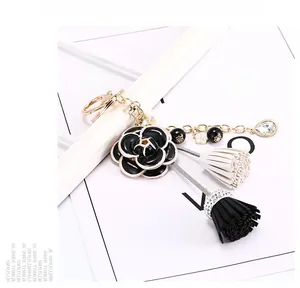 Détail du pendentif fleur de camélia noir avec perles blanches et pompons en cuir chic