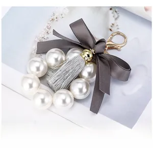 Détail d'un porte-clés perle avec nœud en soie grise et pompon élégant sur un magazine