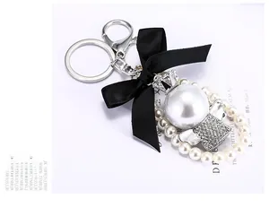 Detail eines eleganten Perlenanhängers mit schwarzer Schleife und kleiner Krone am Ring