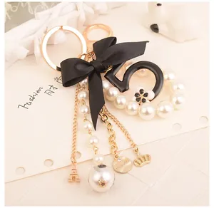 Detail of keychain with black number 5, satin bow, faux pearls and Eiffel Tower charm