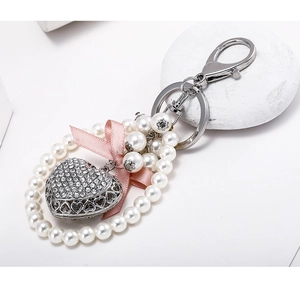 Detailed close-up of a pearl keychain featuring a pink silk bow and a crystal heart pendant