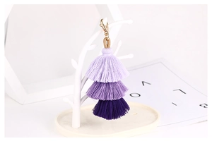 Close-up of triple-layered purple gradient tassel charm with golden lobster clasp and cord