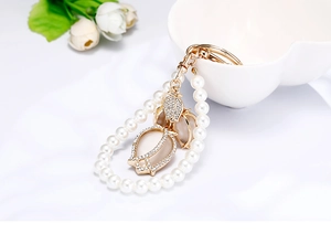 Detail showing pearl tulip keychain with golden metal finish and inlaid opal stone