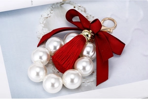 Détail d'un porte-clés en perles avec pompon rouge, nœud en satin et fermoir doré