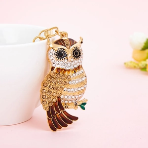 Porte-clés hibou luxueux doré avec cristaux et émail sur un fond rose élégant