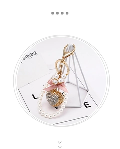 Detail of heart keychain with pink bow, rhinestones, and pearls on gold lobster clasp