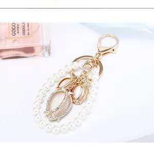 Detail of tulip cat eye stone pendant with pearls and rhinestones on a golden keychain