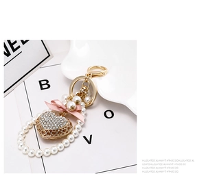 Detail view of heart keychain with rhinestones, pearls and a pink silk bow