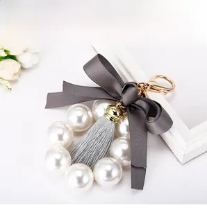 Détail du porte-clés en perles avec nœud en satin gris foncé et élégant pompon