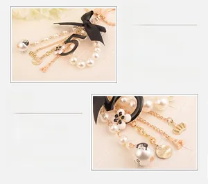 Detail of keychain featuring a black satin bow, number 5 charm, and pearl bead string