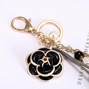 Porte-clés élégant fleur de camélia noire avec perle et détails dorés raffinés
