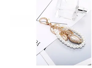 Detail of tulip keychain with cat-eye stone, pearls, and crystals on golden alloy