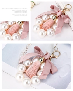 Détail d'un porte-clés nœud rose avec perles blanches et pompon en fil de soie