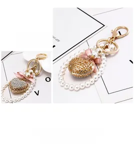 Detail of elegant gold heart keychain featuring white pearls and a pink ribbon bow