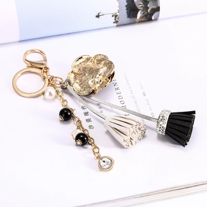 Porte-clés fleur dorée avec perle, perles noires, cristal et pompon bicolore élégant
