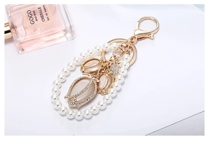 Detail of gold keychain featuring pearl ring and tulip pendants with pink cat eye stones
