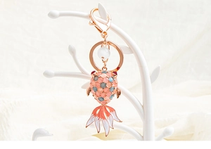 Macro shot of rose gold koi fish keychain with cat-eye stone and enamel detailing
