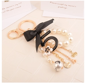 Detail view of bow keychain with pearl beads, number five pendant and golden charms