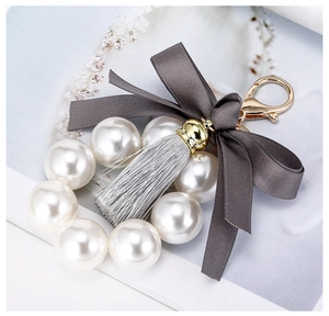 Détail d'un porte-clés en perles avec un nœud en satin gris et des glands en soie