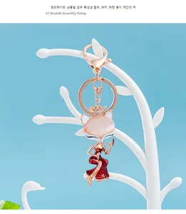 Detail view of pink fox keychain with red enamel dress and crown on jewelry stand