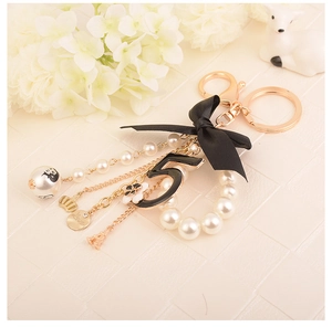 Detail view of pearl keychain with black bow, number 5 charm, and golden Eiffel Tower
