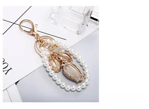 Detail of tulip keychain with cat-eye stone, pearls, and crystals on golden alloy