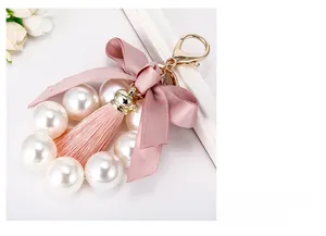 Détail du porte-clés à nœud en satin rose avec glands et grandes perles blanches