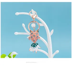 Detail of goldfish keychain with cat eye stones and colorful enamel on a jewelry stand