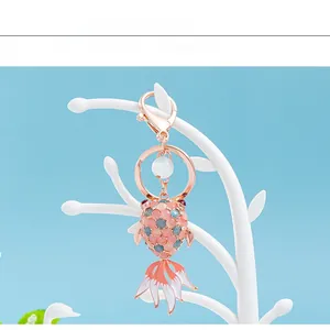 Macro detail of rose gold goldfish keychain with opal stones on a light blue background