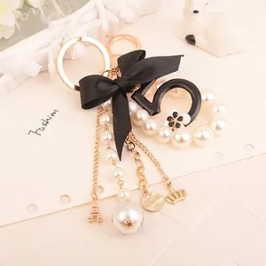 Fashionable keychain featuring a silk bow, pearl strings, and a metallic number five charm