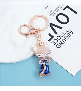 Detail of fox keychain featuring pink opal head and elegant blue enamel cheongsam dress